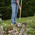 Person gardening with a hoe in a garden setting