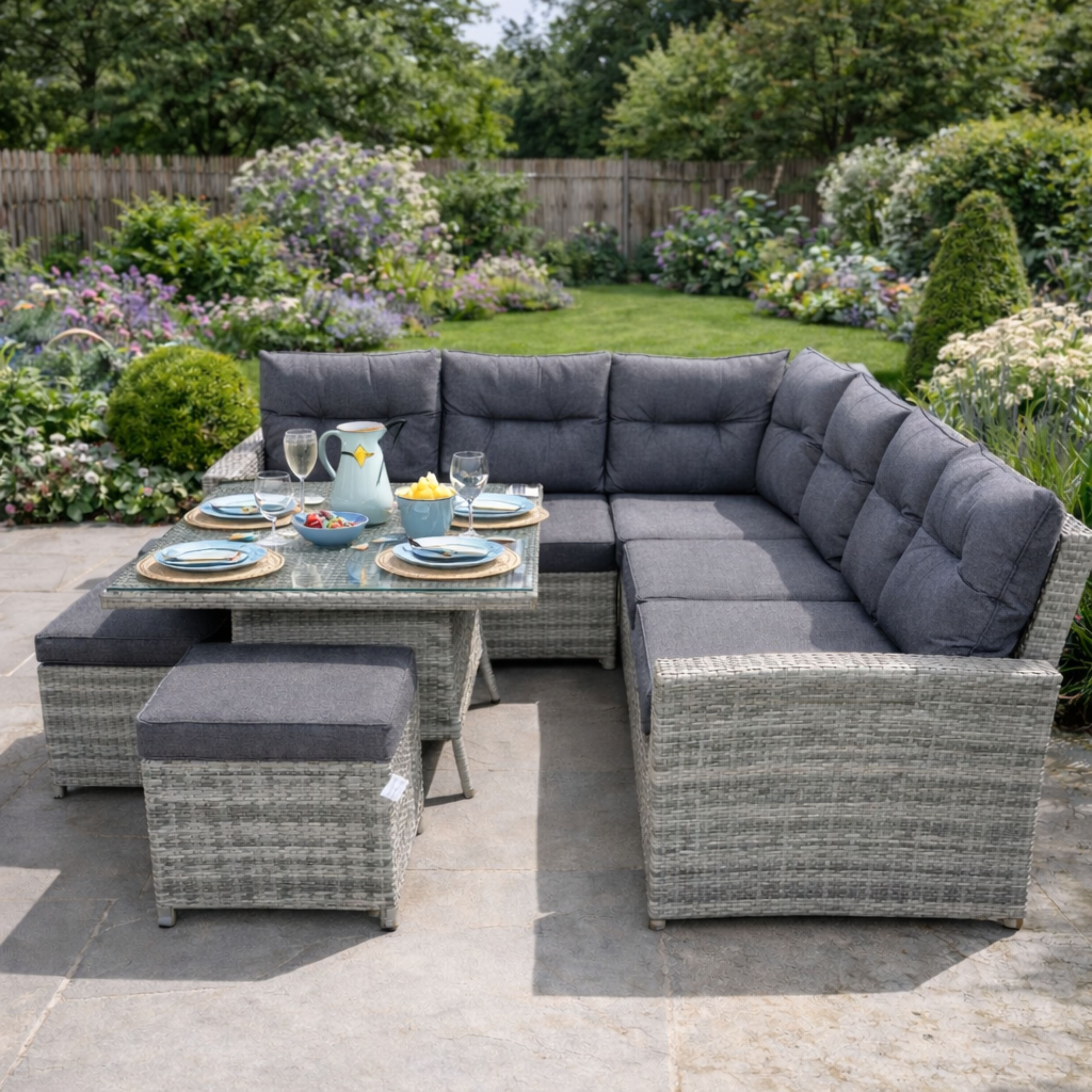 Gray outdoor sectional sofa with cushions and a small table set for a meal in a garden.