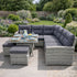 Gray outdoor sectional sofa with cushions and a small table set for a meal in a garden.