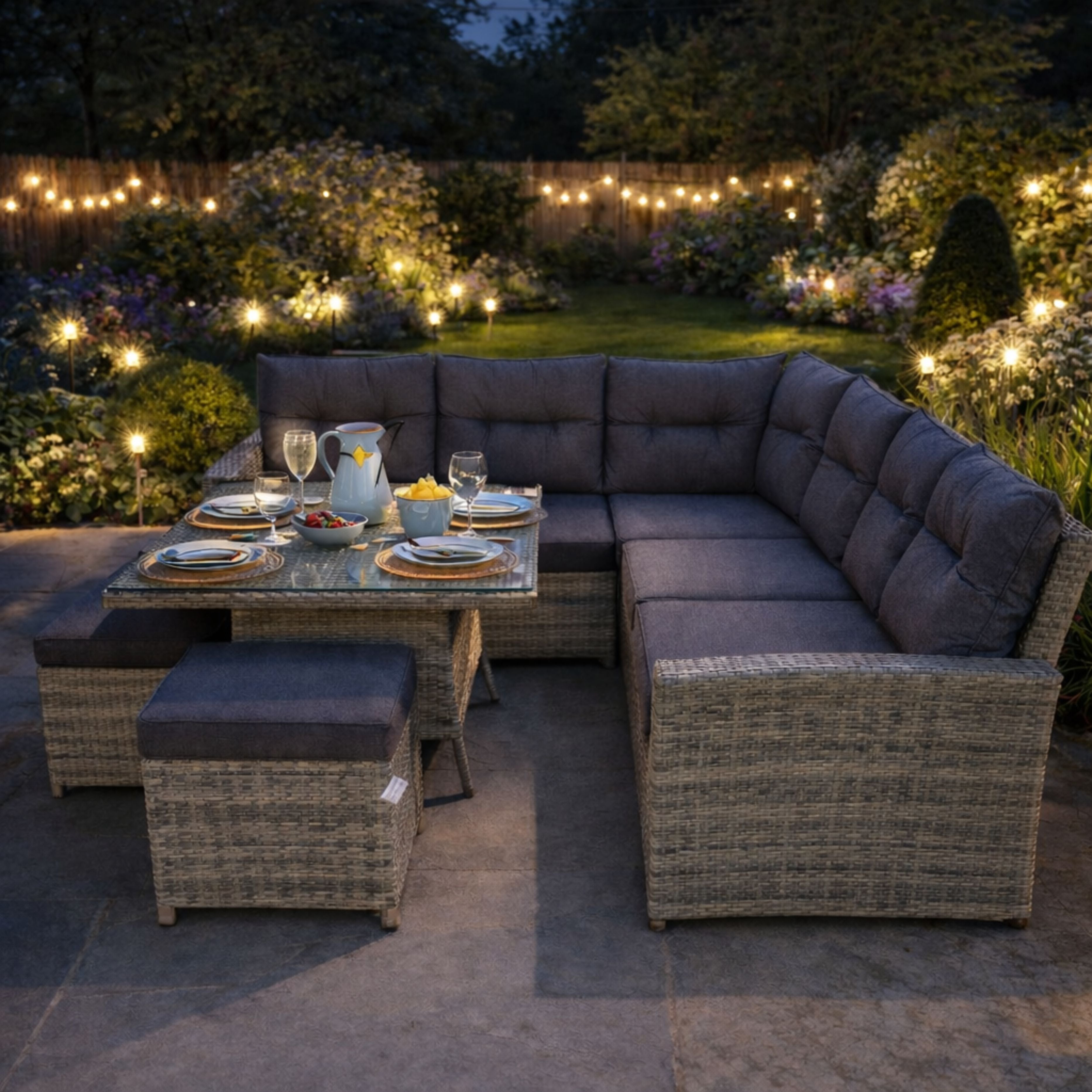 Outdoor patio set with table and chairs under string lights in a garden.