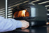 Person interacting with a Gozney pizza oven in a kitchen setting