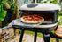 Portable pizza oven with a pizza inside, set outdoors.