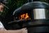 Person interacting with a black outdoor pizza oven with visible flames.