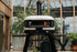 Outdoor pizza oven with visible flame inside, set against a wooden and glass background.