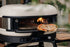 Portable pizza oven with a pizza being cooked outdoors