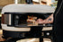 Person putting wood into a wood fire pizza oven