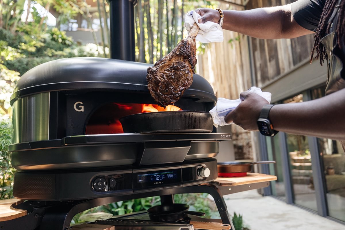Person grilling a large piece of meat on a Gozney Pizza oven